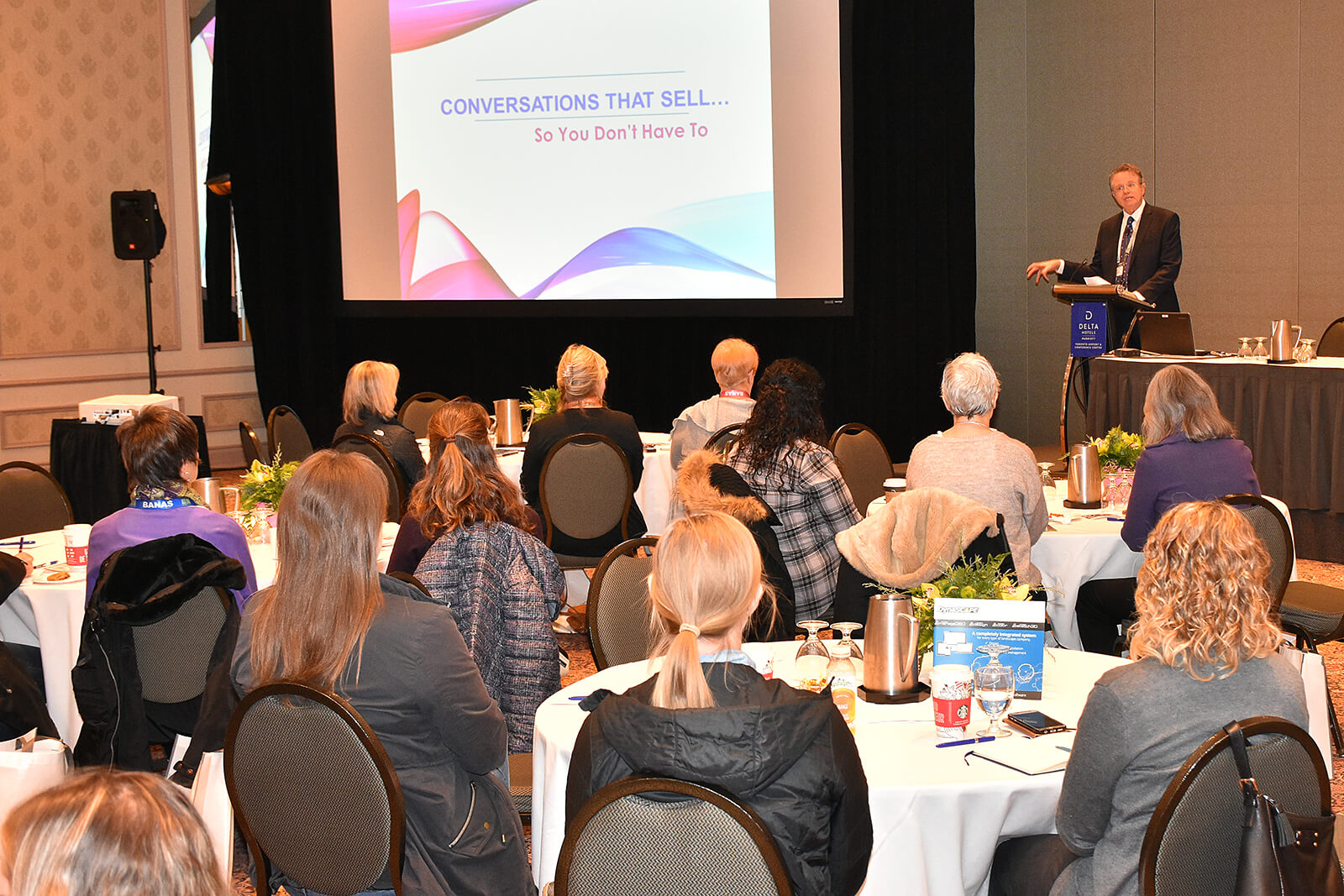 presenter speaking to a crowd in a large room