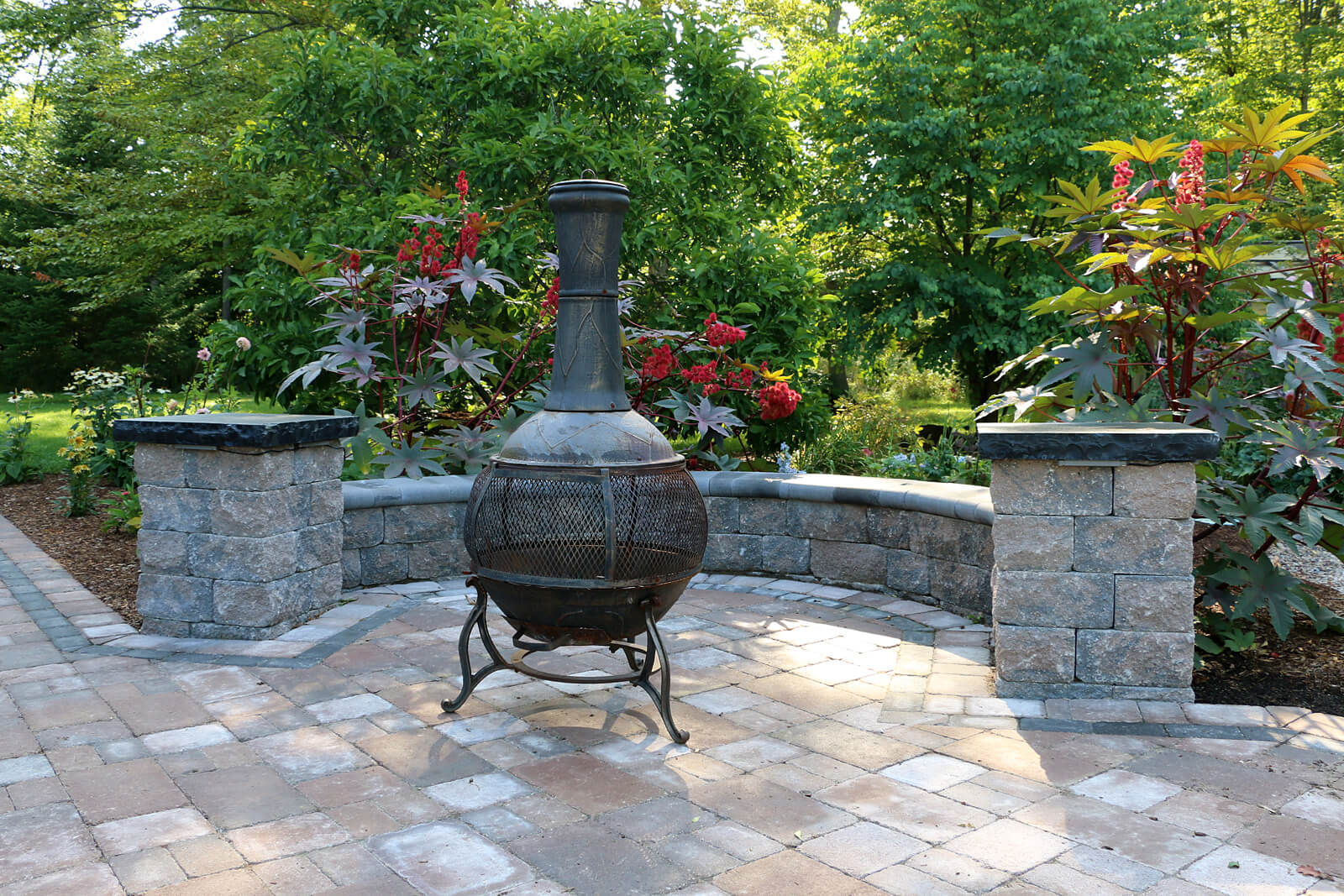stone patio area with retaining wall and black chiminea