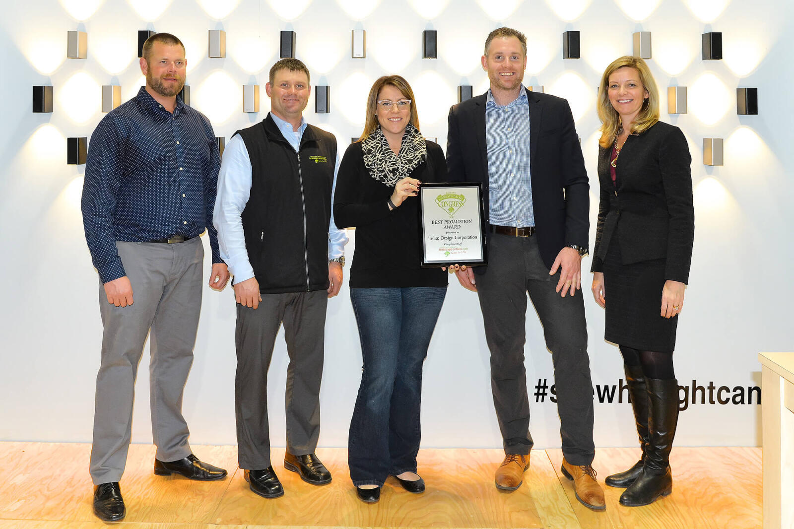 five people standing in a booth holding an award