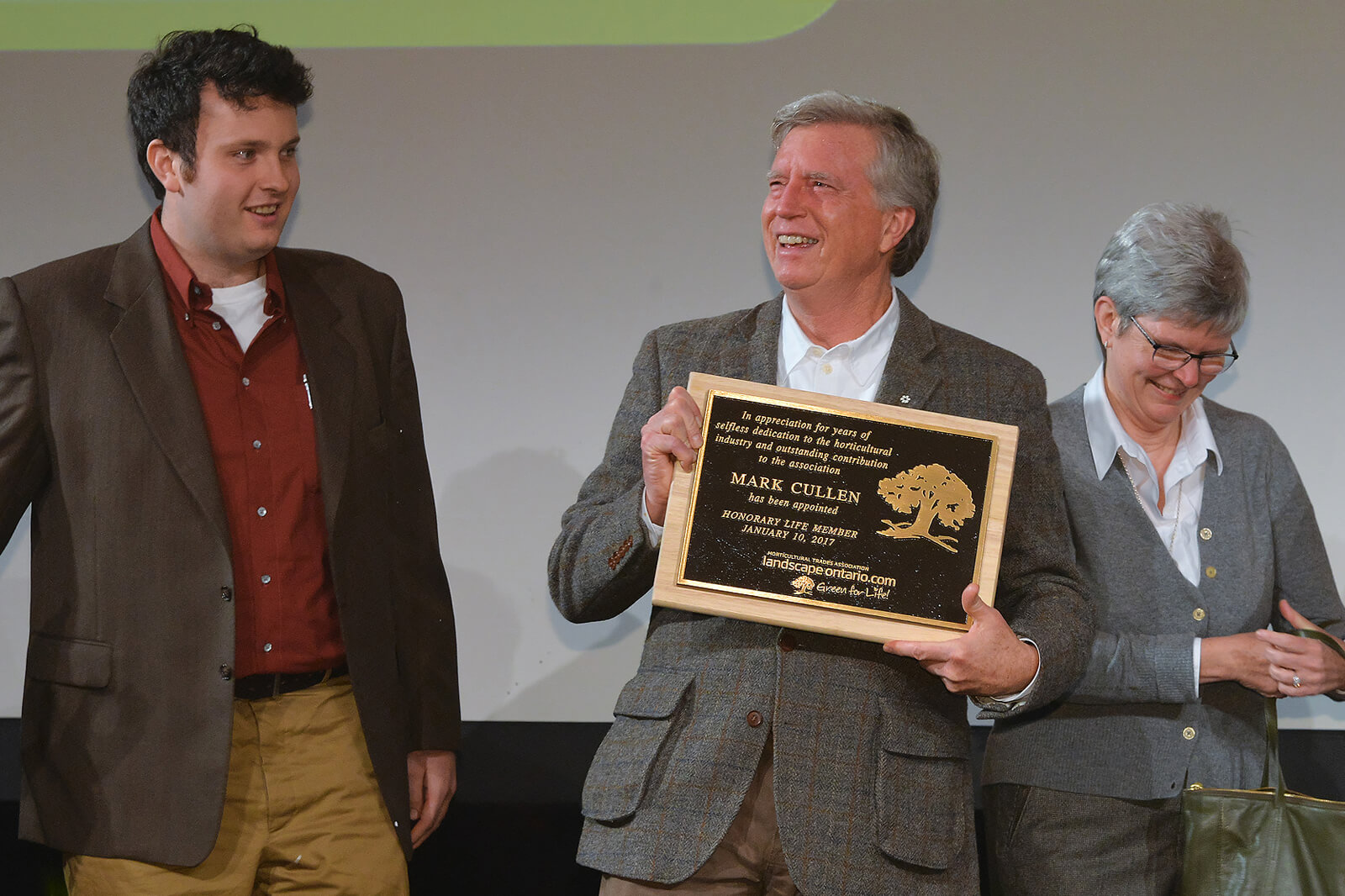 mark cullen holding an award on stage next to his son, Ben Cullen