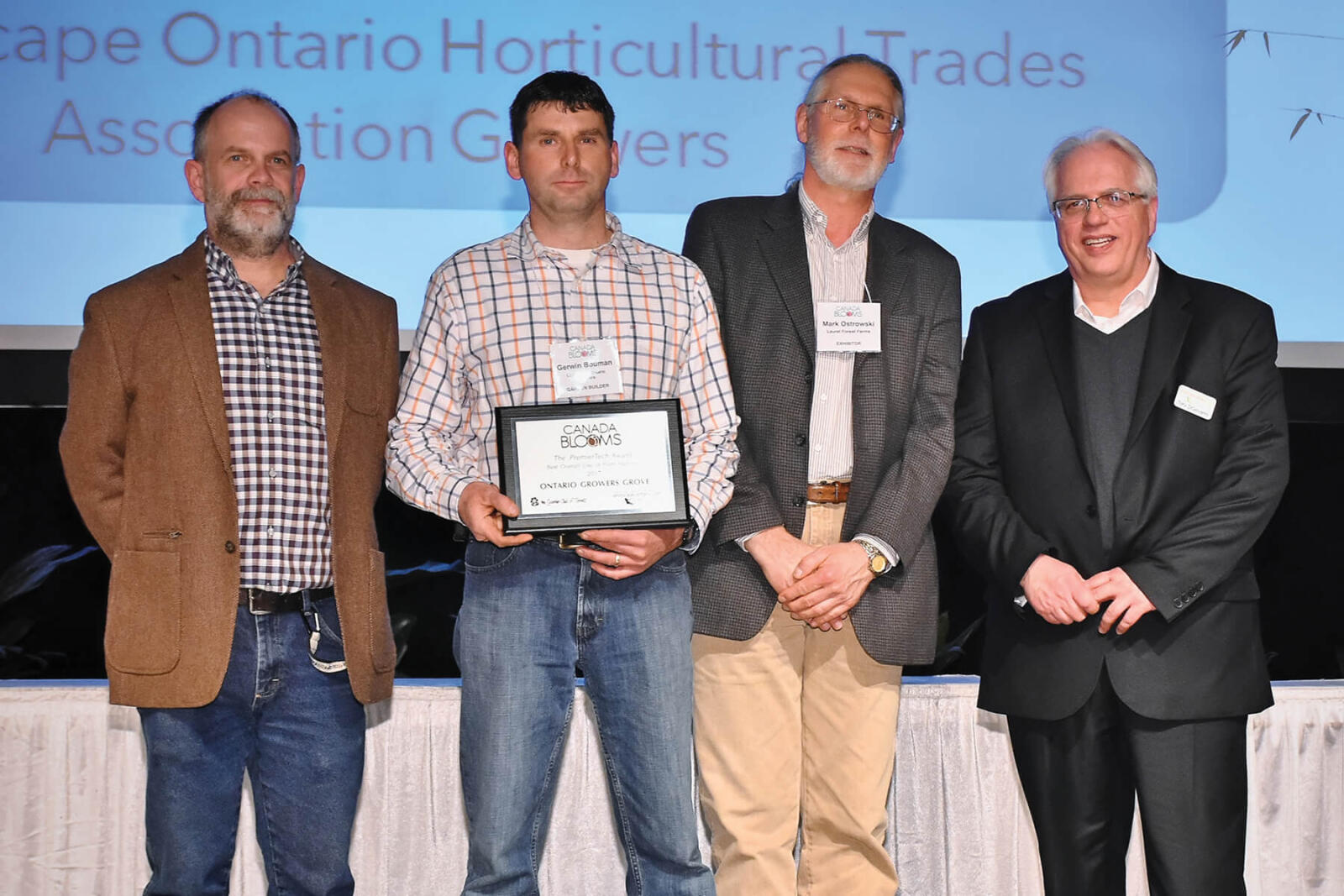 four men on stage. one holding an award plaque