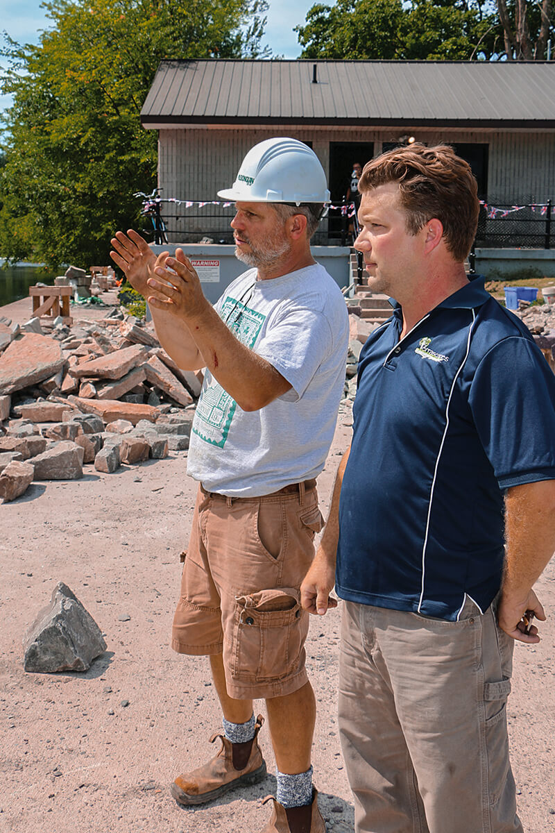 two men talking on a construction site by the river