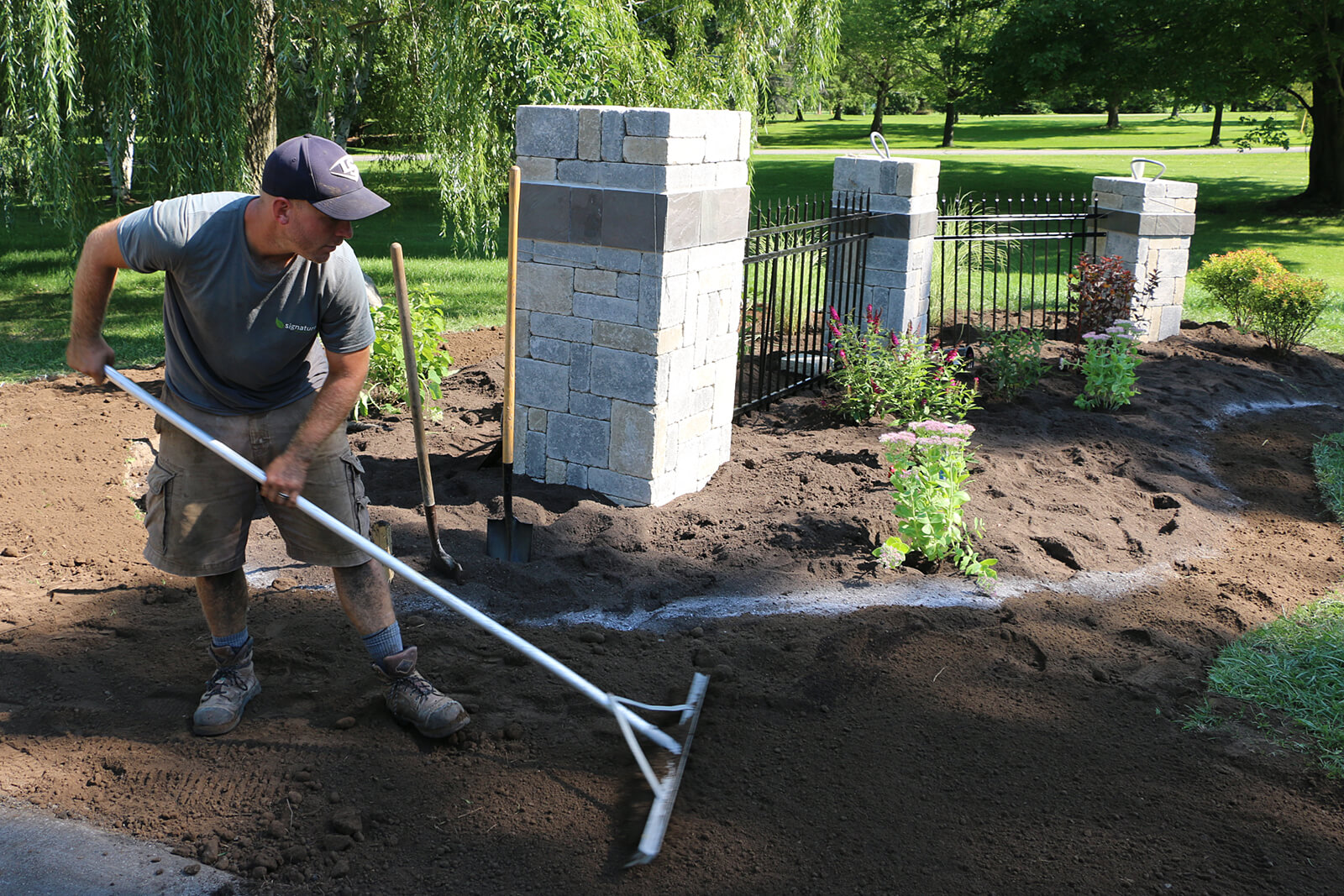 man raking soil before laying sod