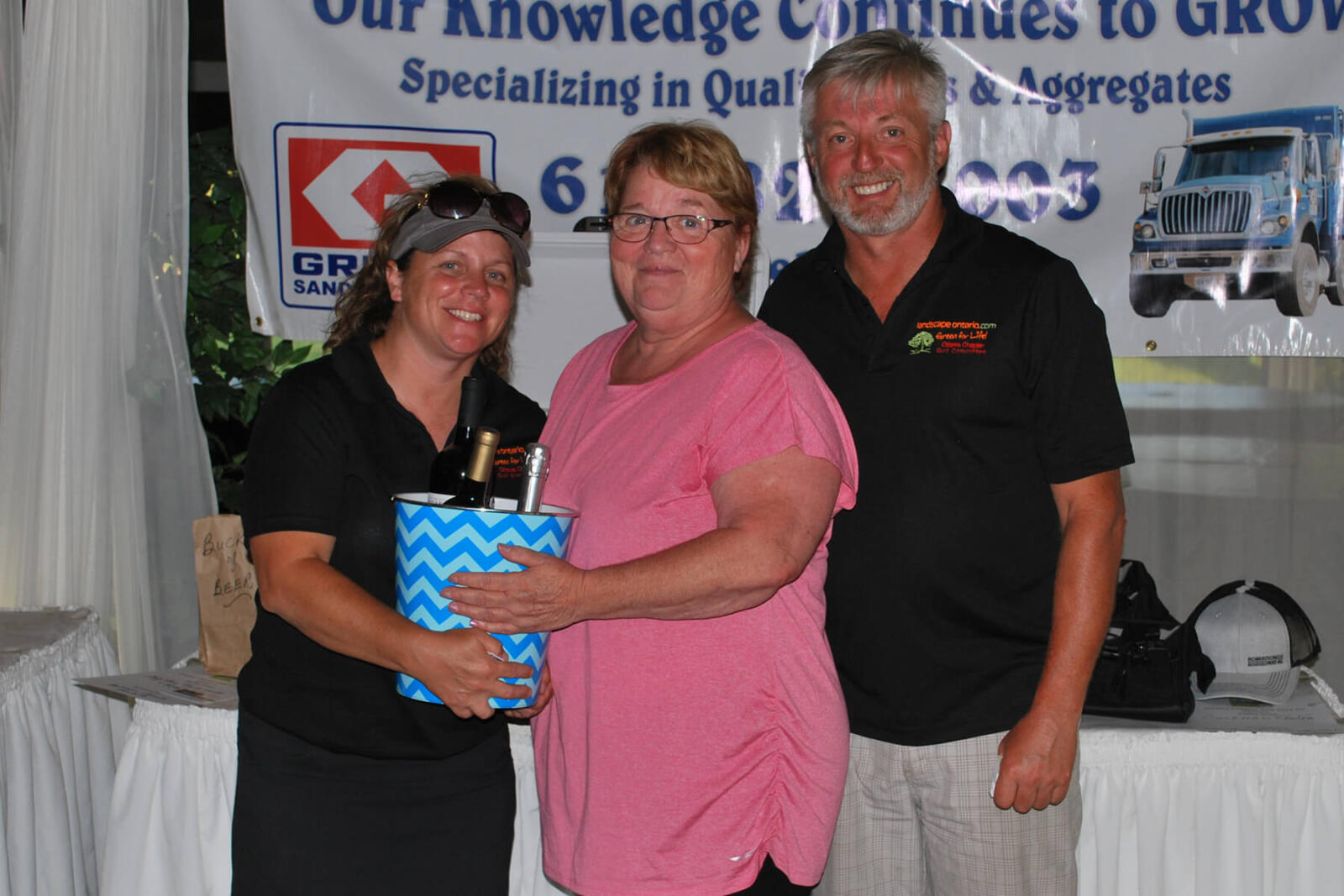 woman accepting a prize from two representatives at a golf tournament