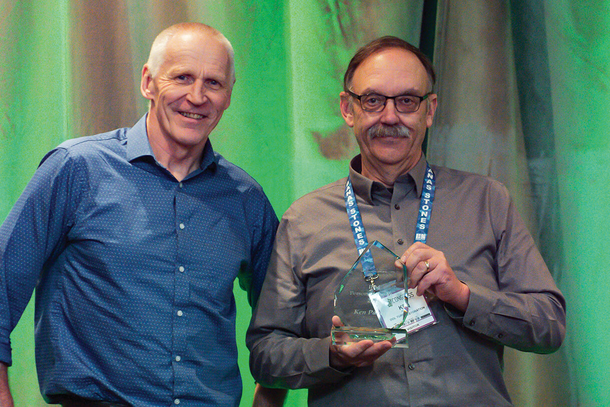 man presenting another with an award on stage