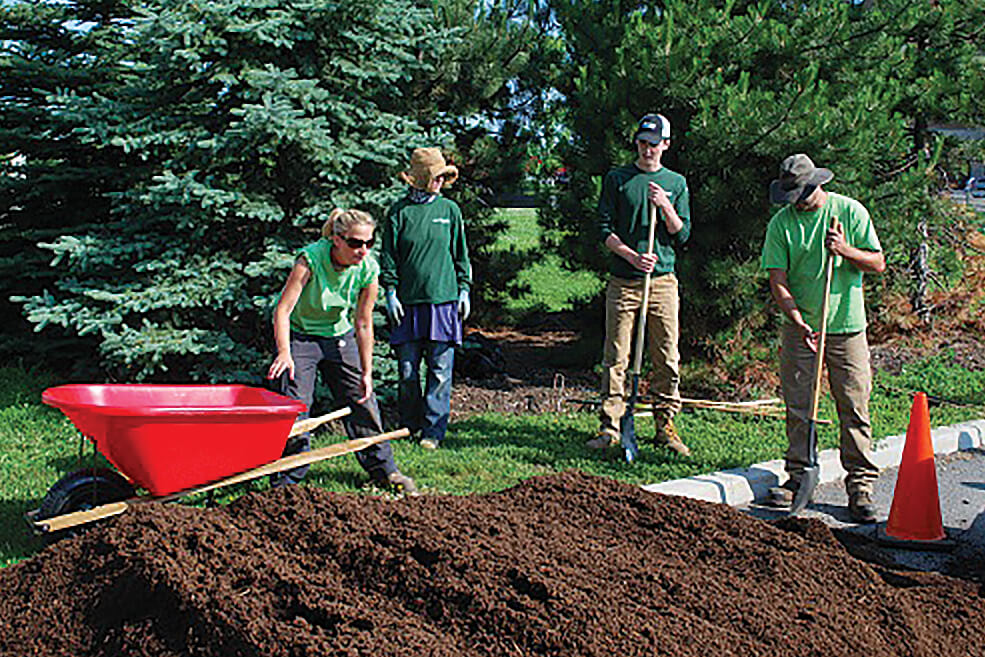 students shoveling mulch