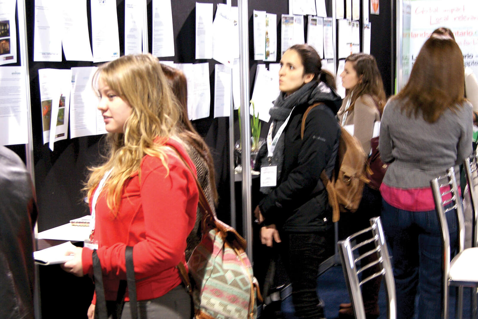 people looking over job posting on a wall
