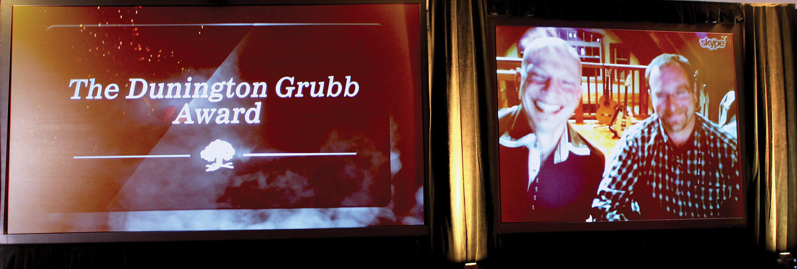 two men on a large video screen via Skype