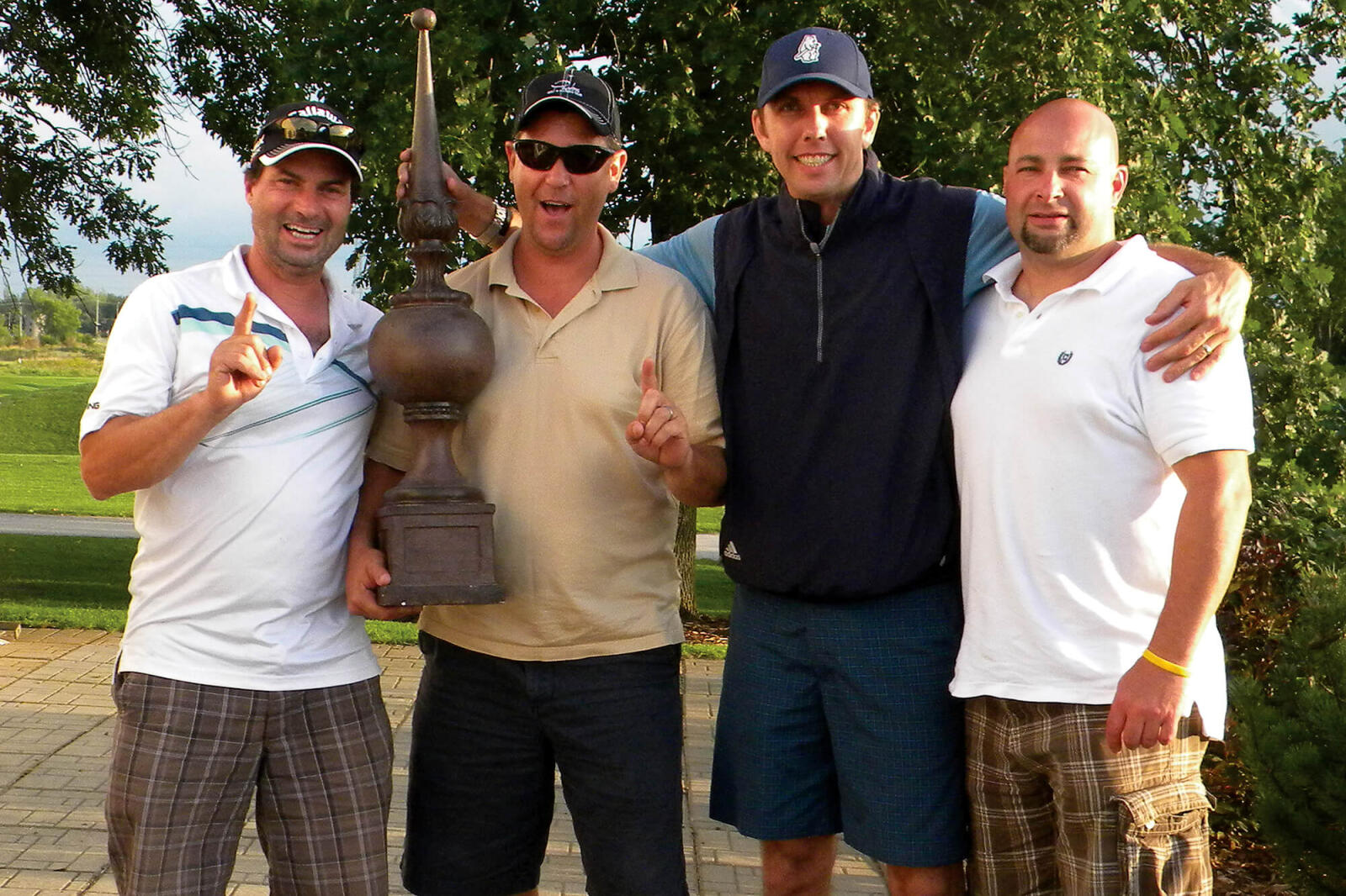 four men posing with a large trophy