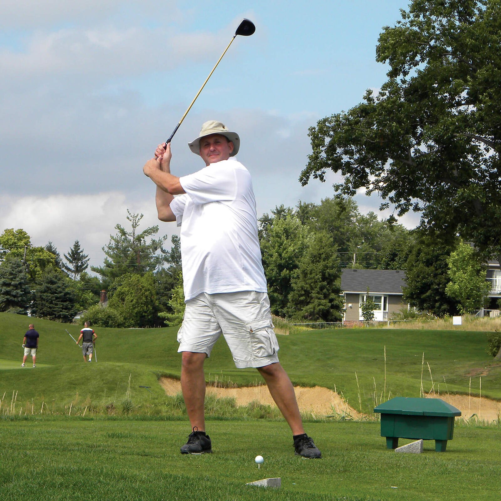 man in white swinging a golf club