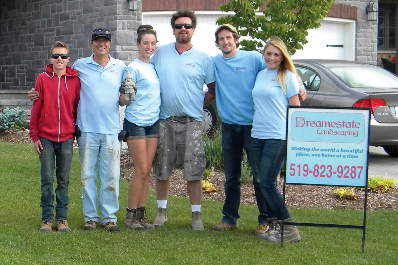 seven people posing on a front yard