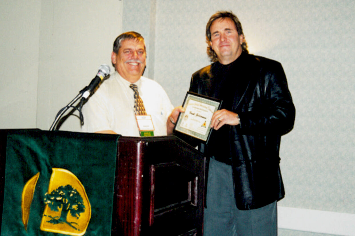 two men at a podium. one accepting a certificate