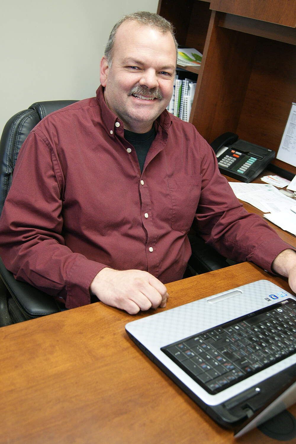 man smiling at a desk using a laptop