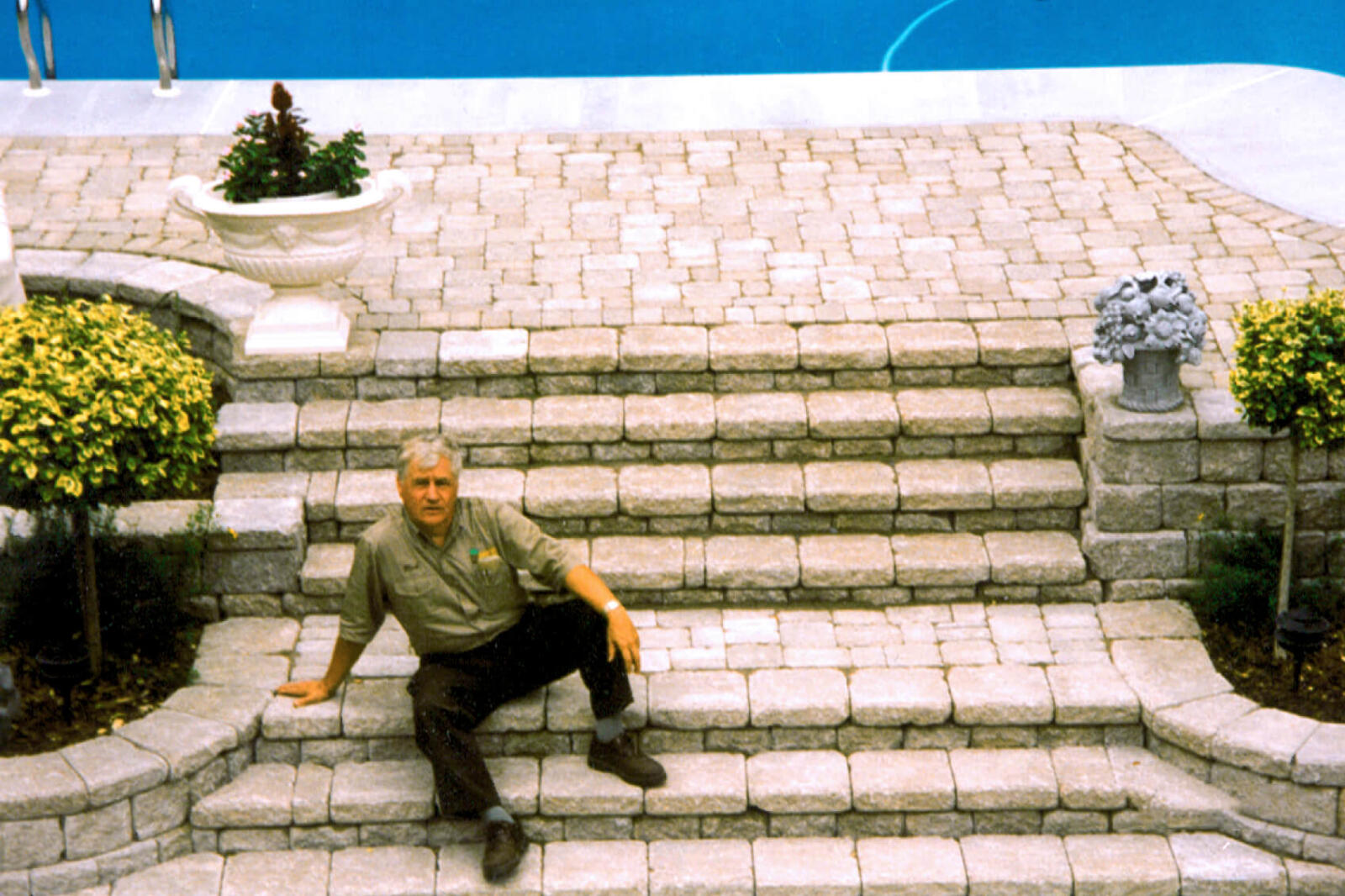 man sitting on interlocking stone steps beside a pool