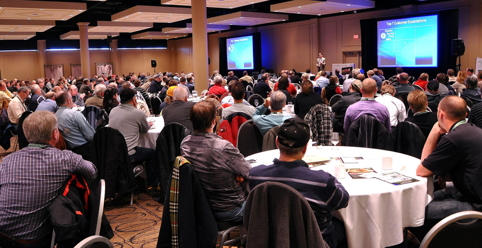 room full of people watching a presenter at the podium