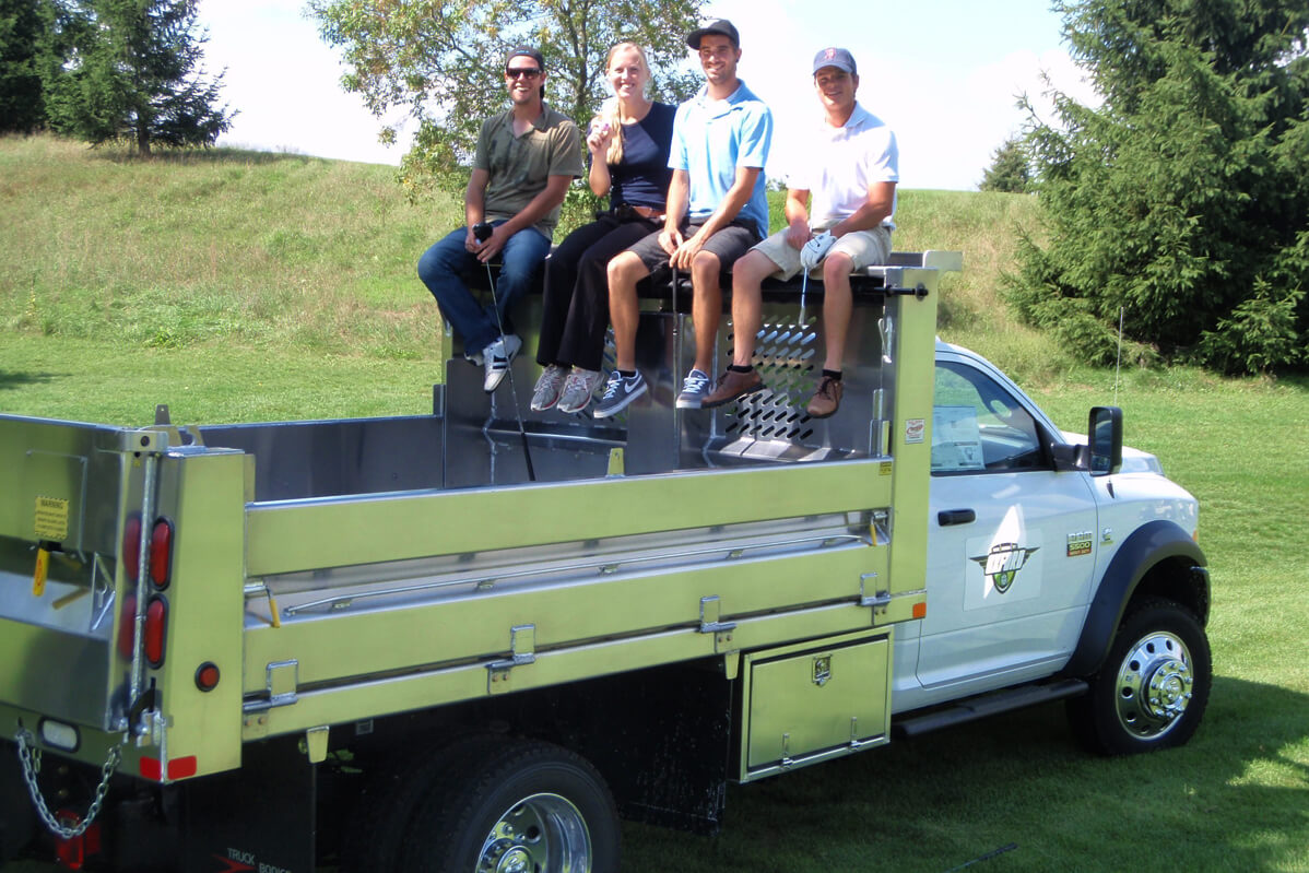 four people sitting in the back of a dump box truck