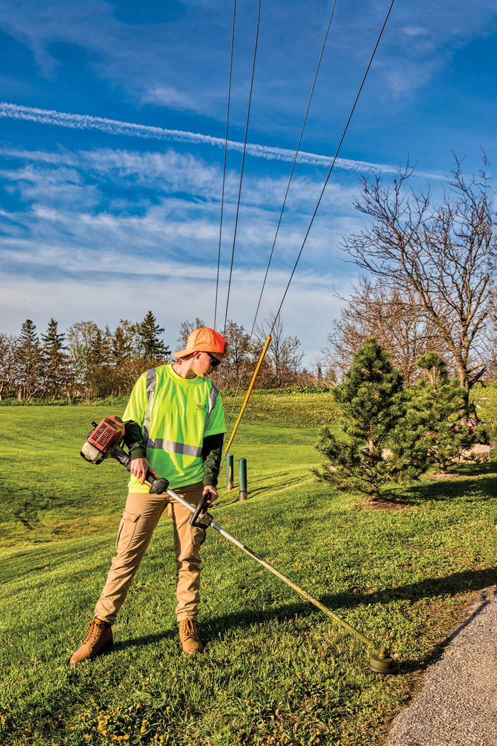 person using a line trimmer to cut grass