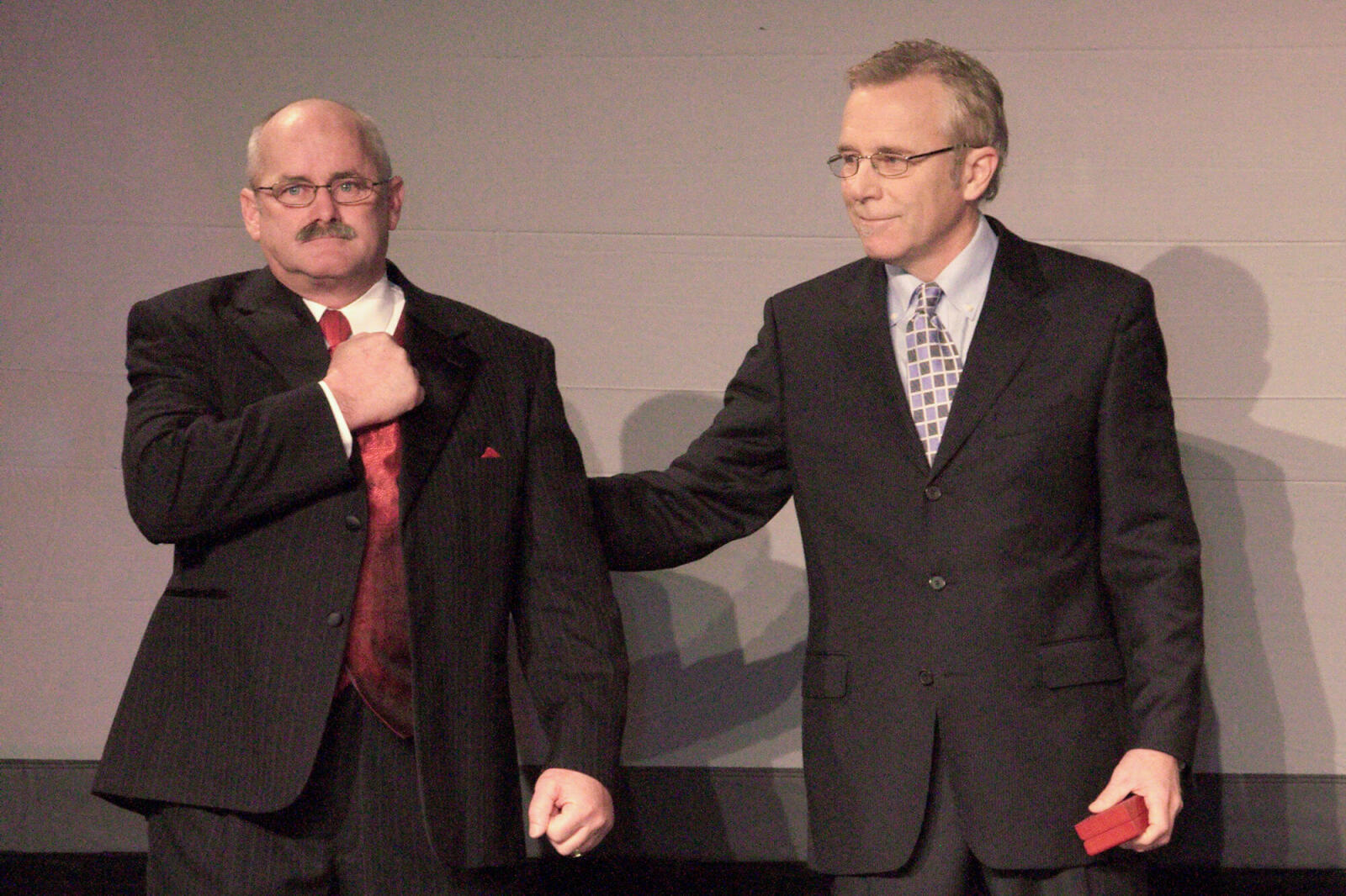 two men in suits on a stage