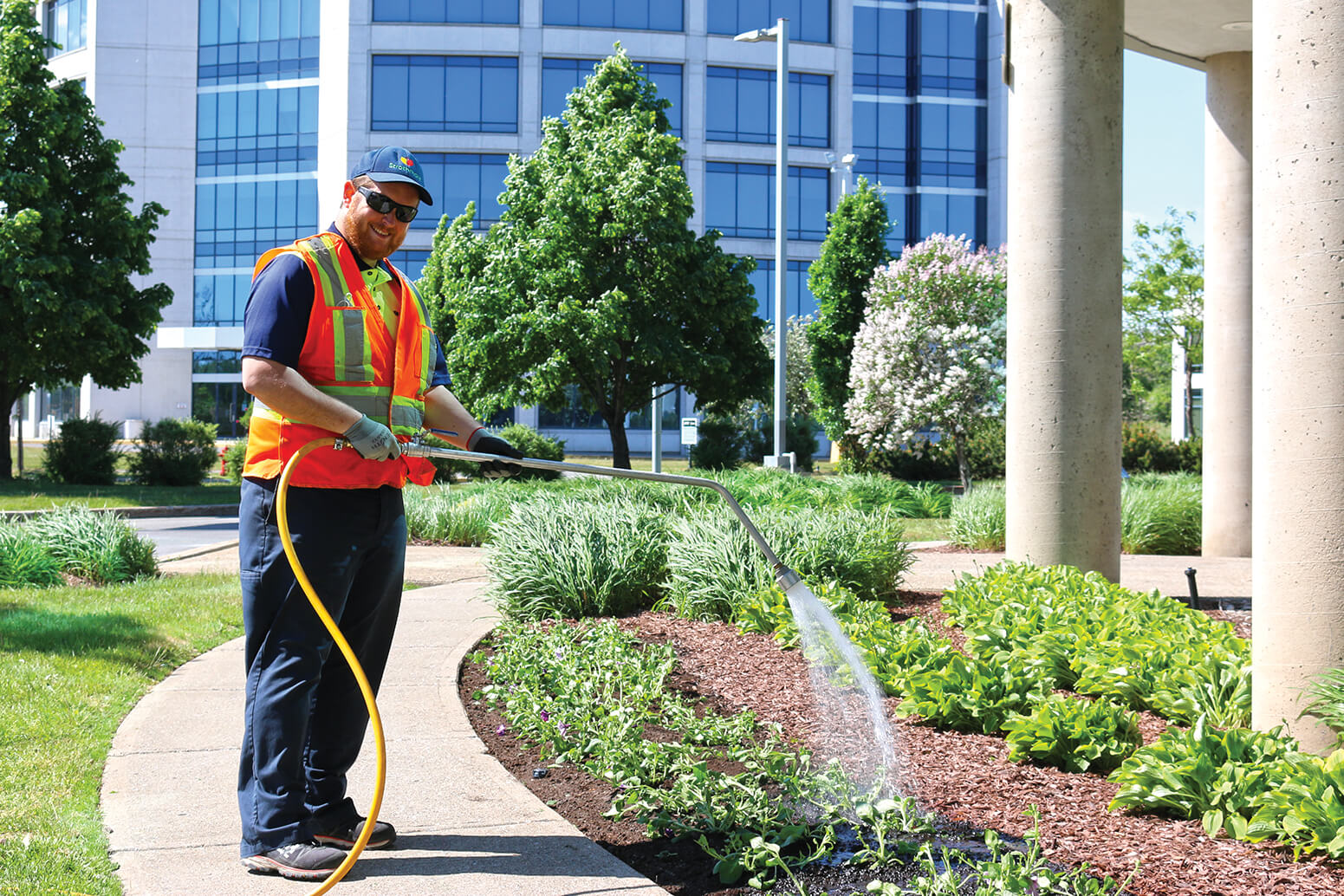 man watering plants outside a building