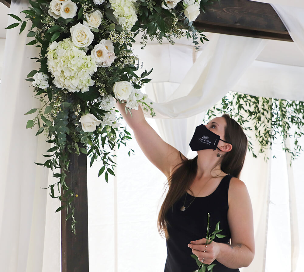 woman working on a tall flower arrangement