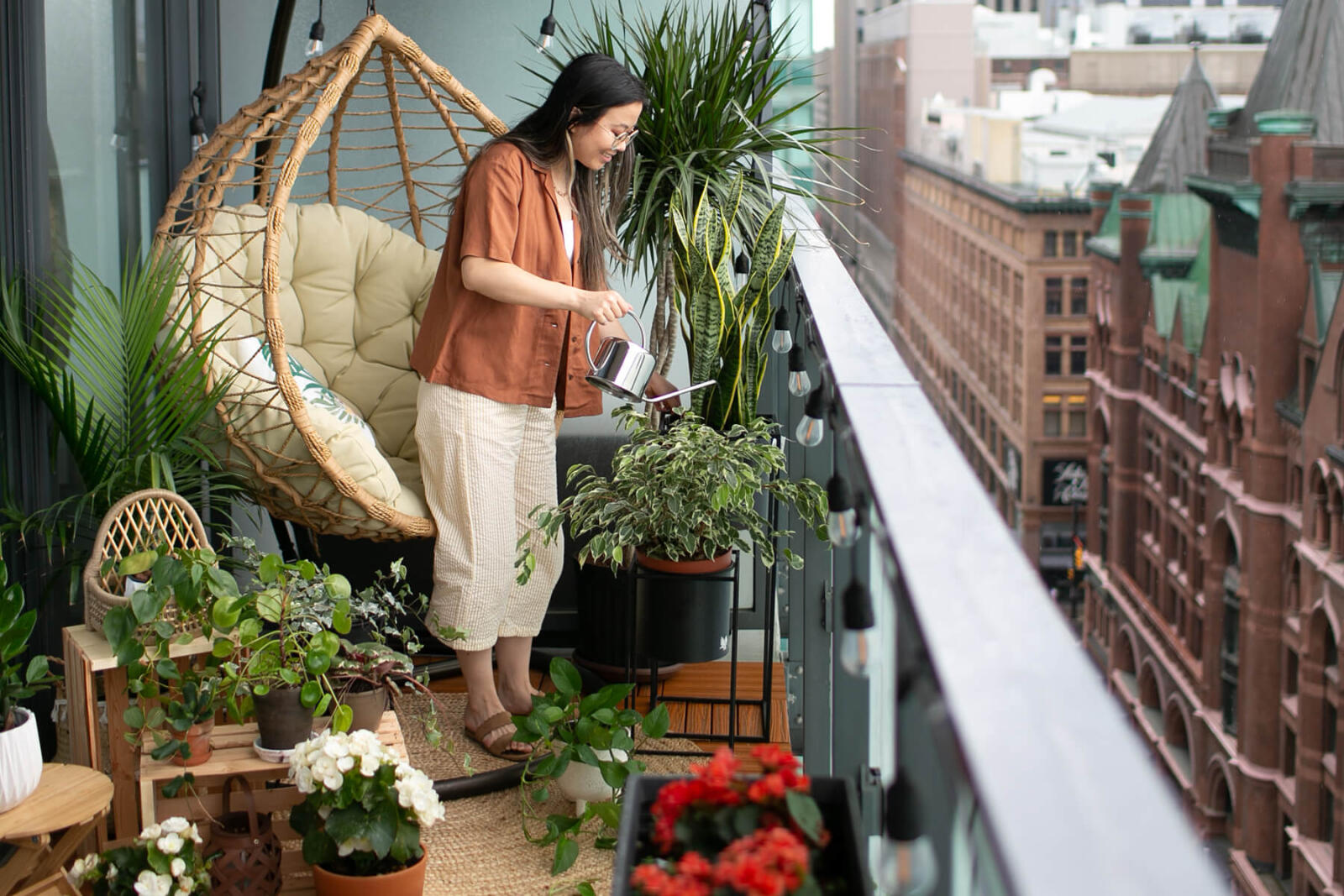 woman watering a plant on a balcony