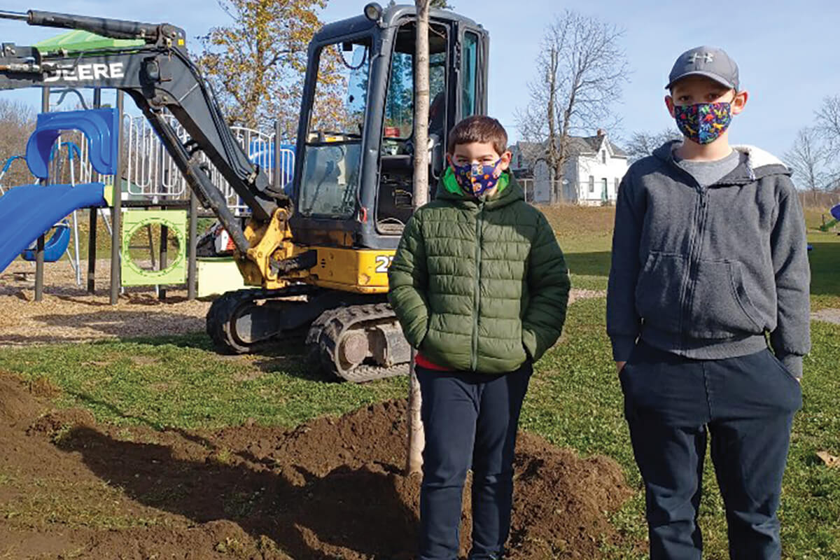 two kids in front of a newly planted tree