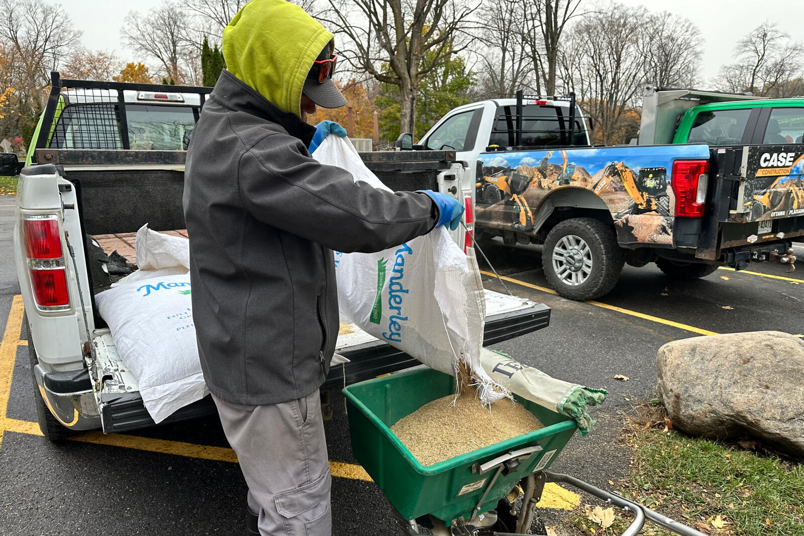 man pouring grass seed into a spreader