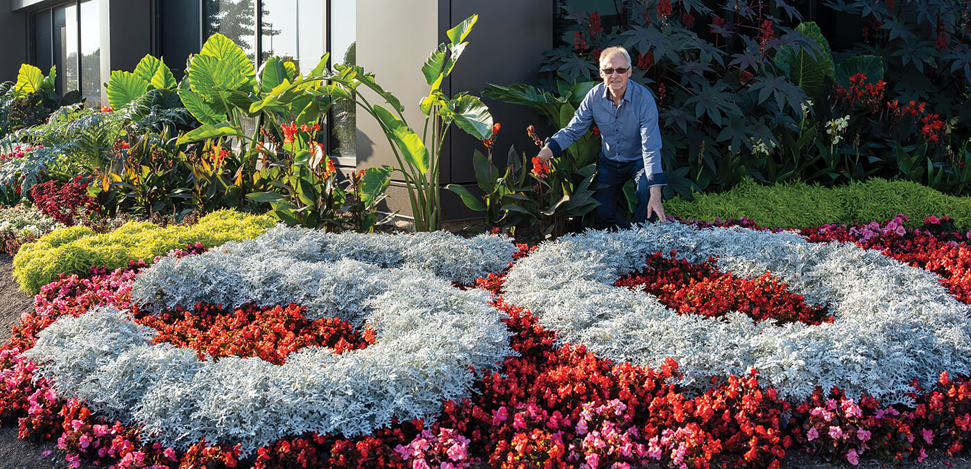 man standing behind plants arranged in the number 50