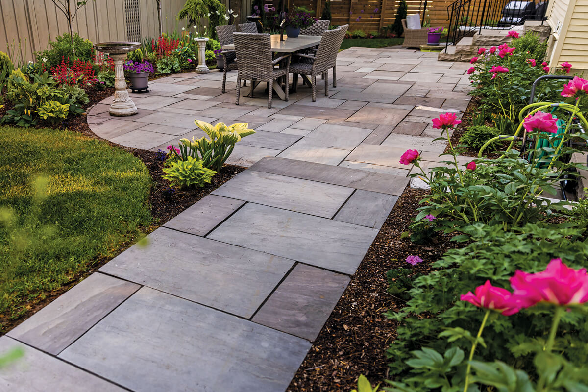 landscaped backyard with a stone path and seating area in the distance