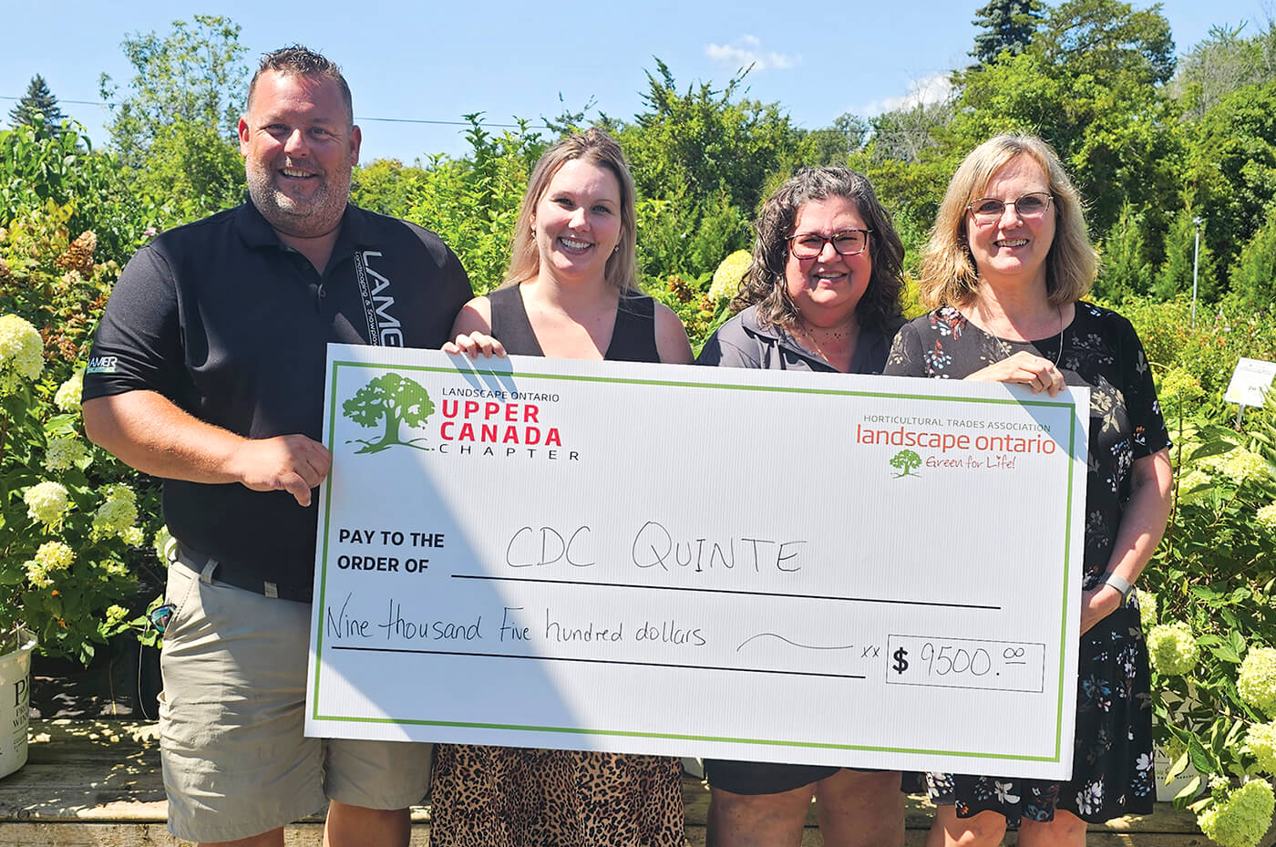 four people holding a large cheque