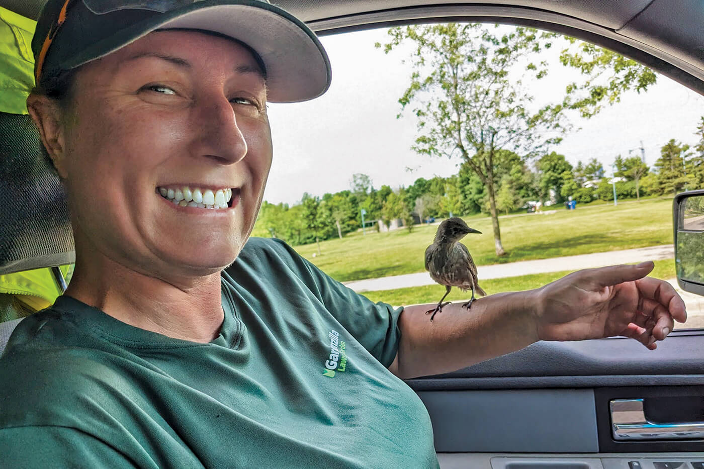 person in a vehicle with a small bird on their arm