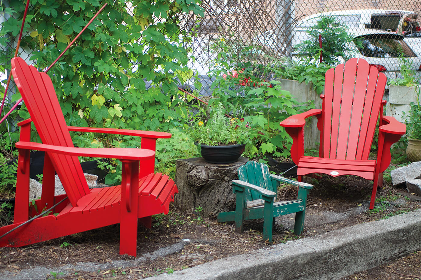 two red muskoka chairs in front of a parking lot