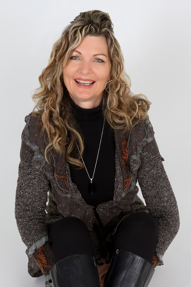 picture of a woman sitting on the floor with her hands under her bent knees and a white background