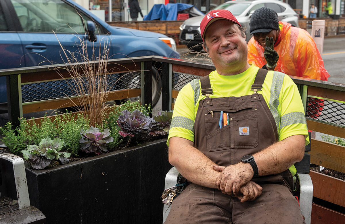 Man sitting on a bench at the side of a busy city street