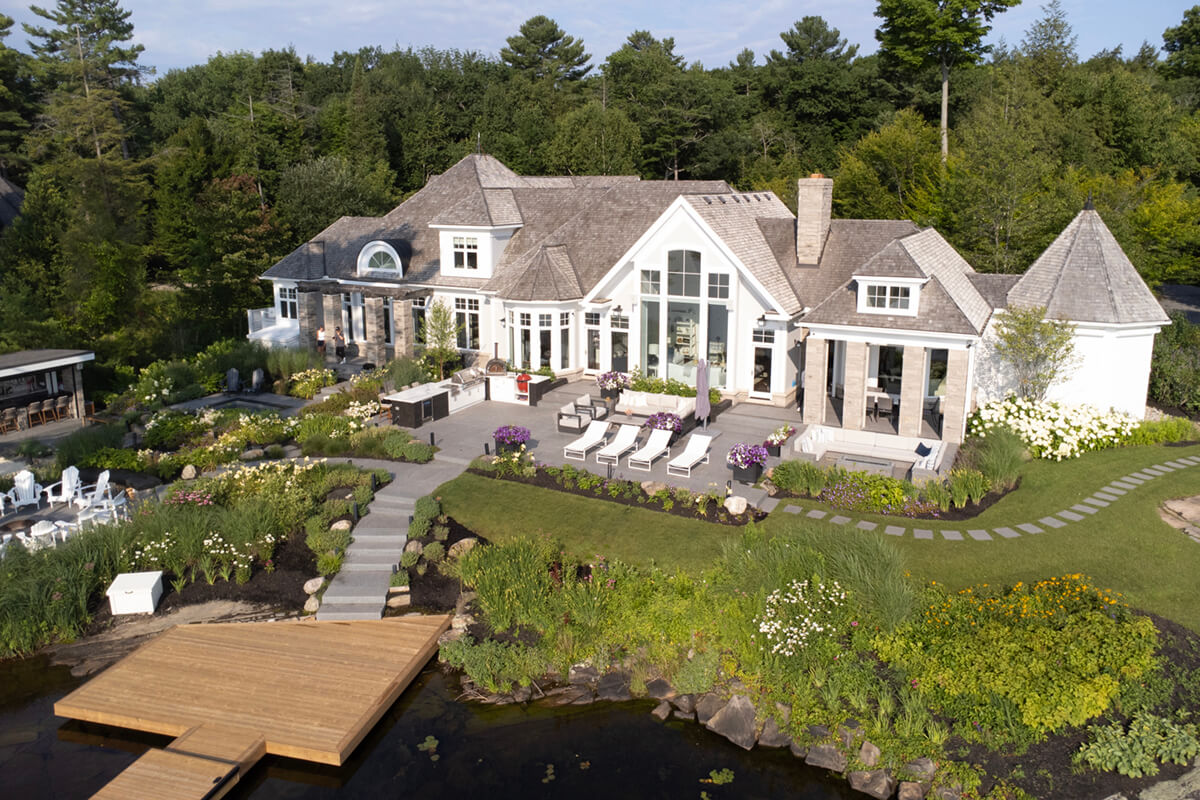 a large home by the water with extensive landscaping on a hillside
