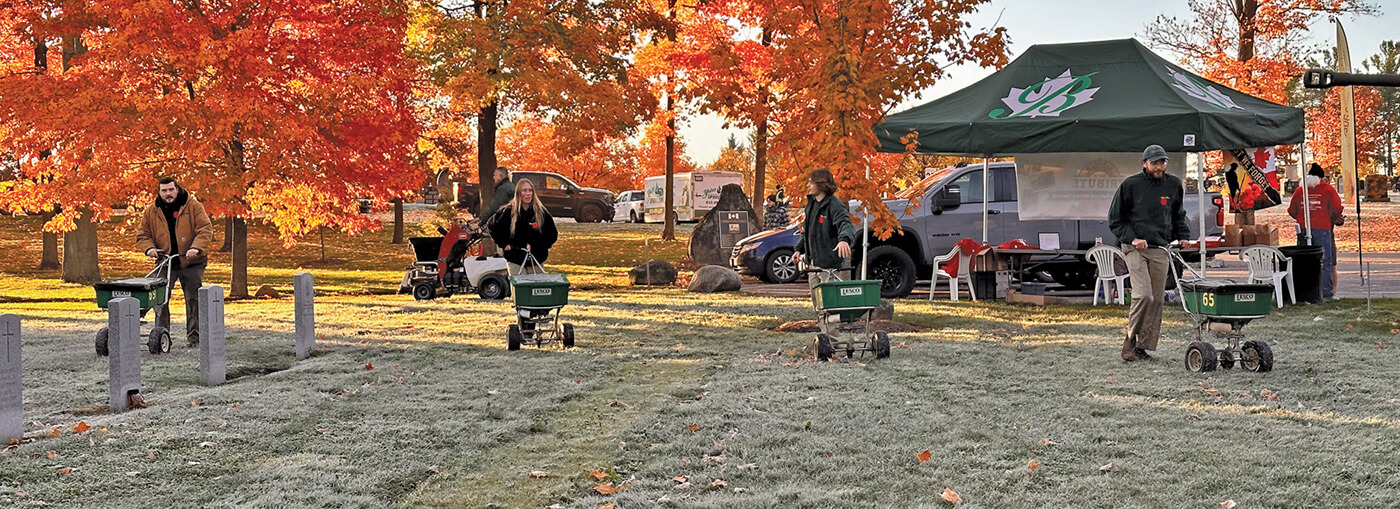 crew out maintaining a cemetery grounds with red leaved fall trees as a backdrop