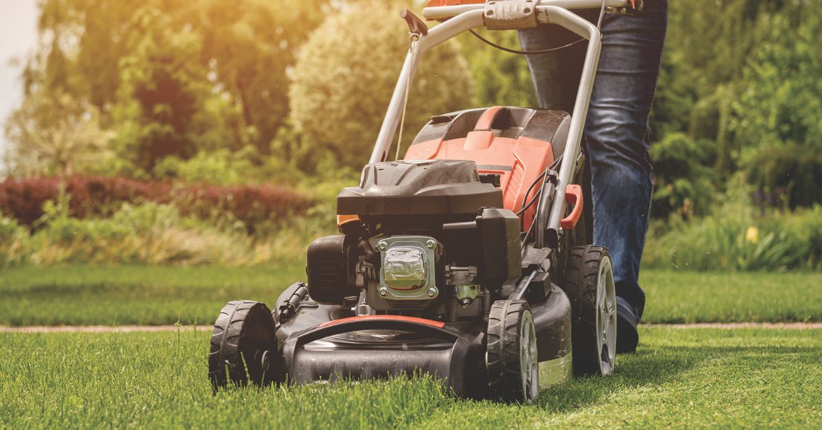 a person using a gas lawnmower