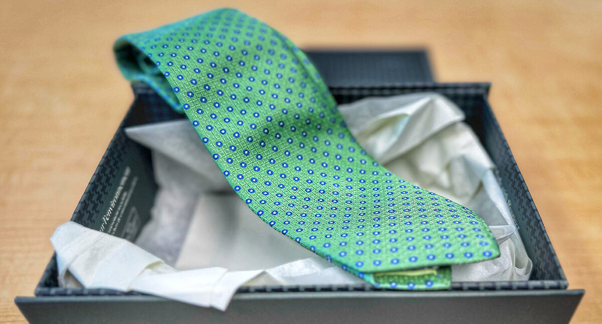 a green tie in a box on a counter top