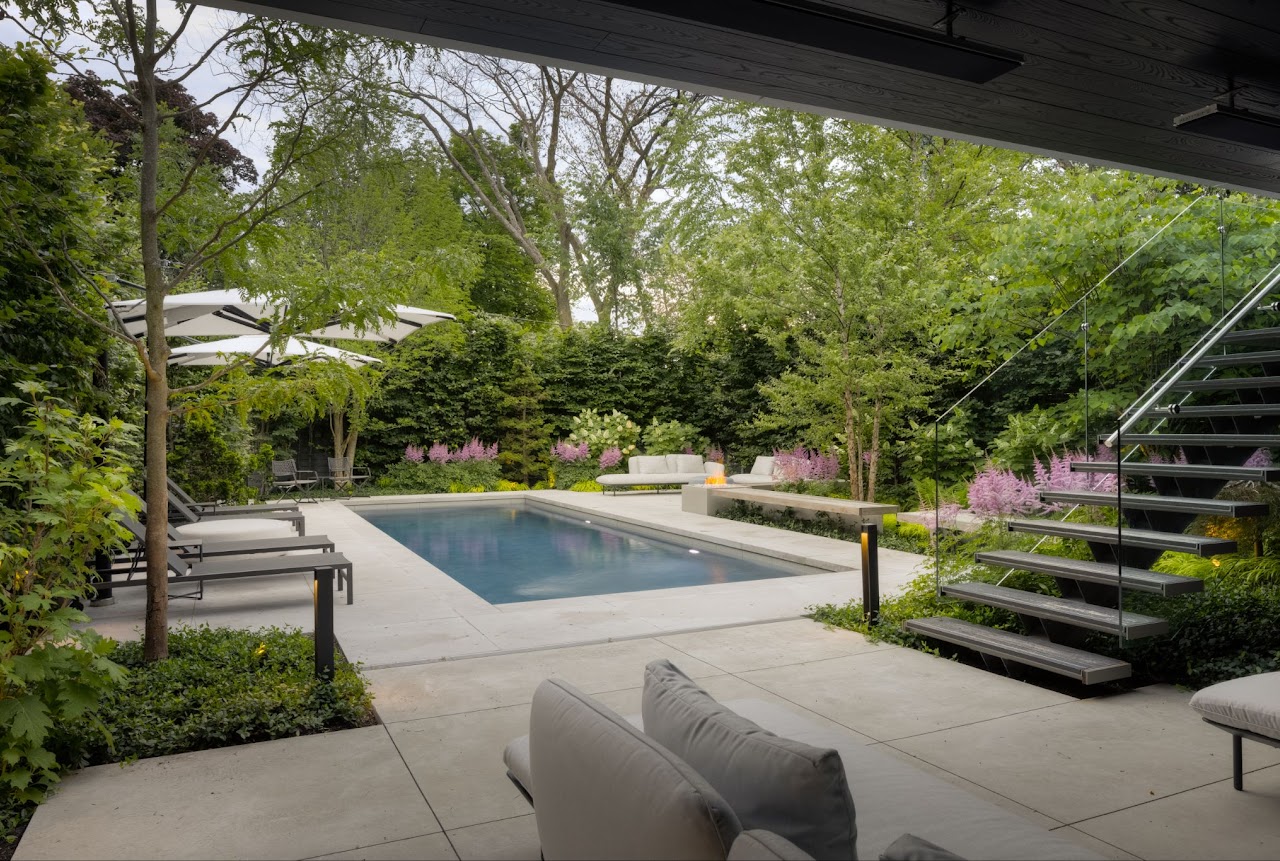 a rectangular pool with plants and trees in the background