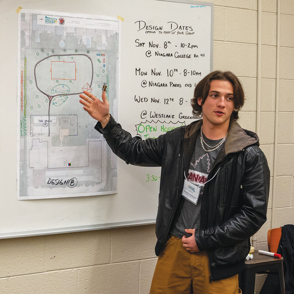 person pointing to a design pinned on a wall