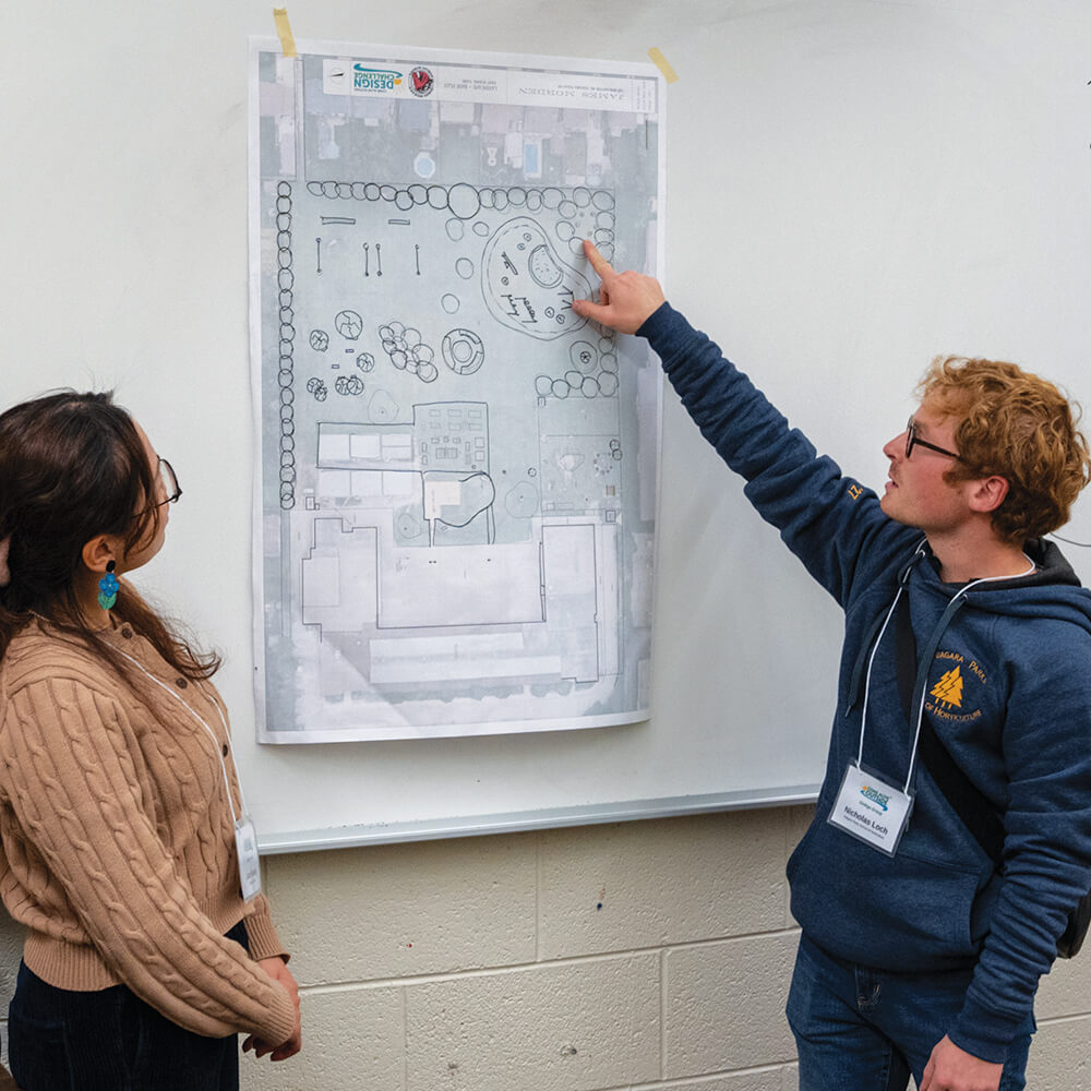 two people looking at a design pinned to a wall