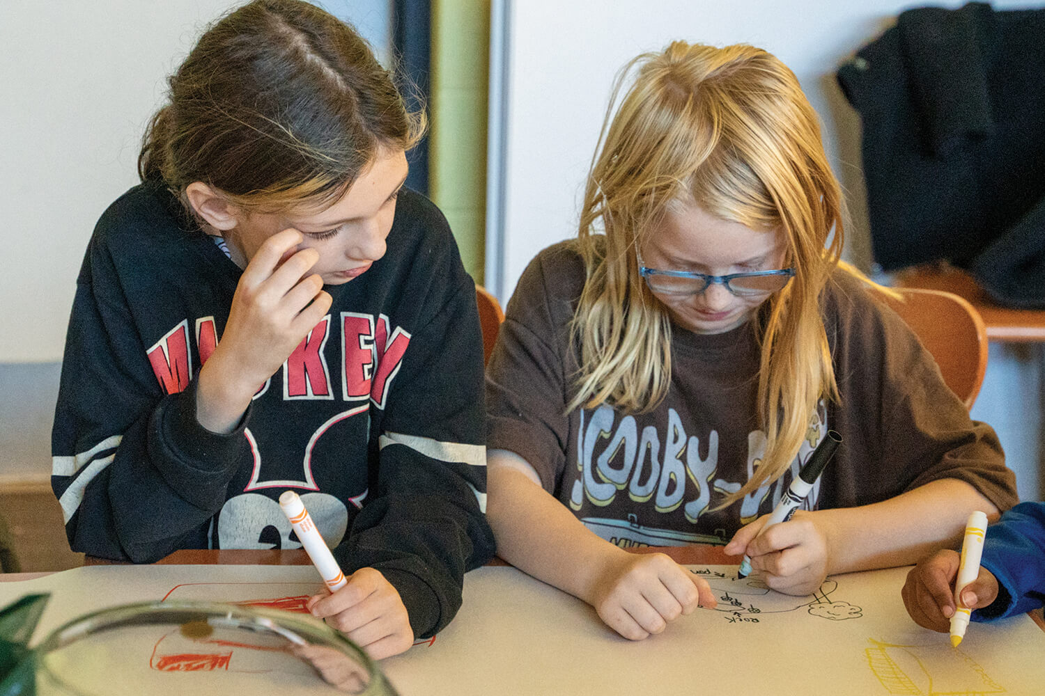 two young girls at a table drawing