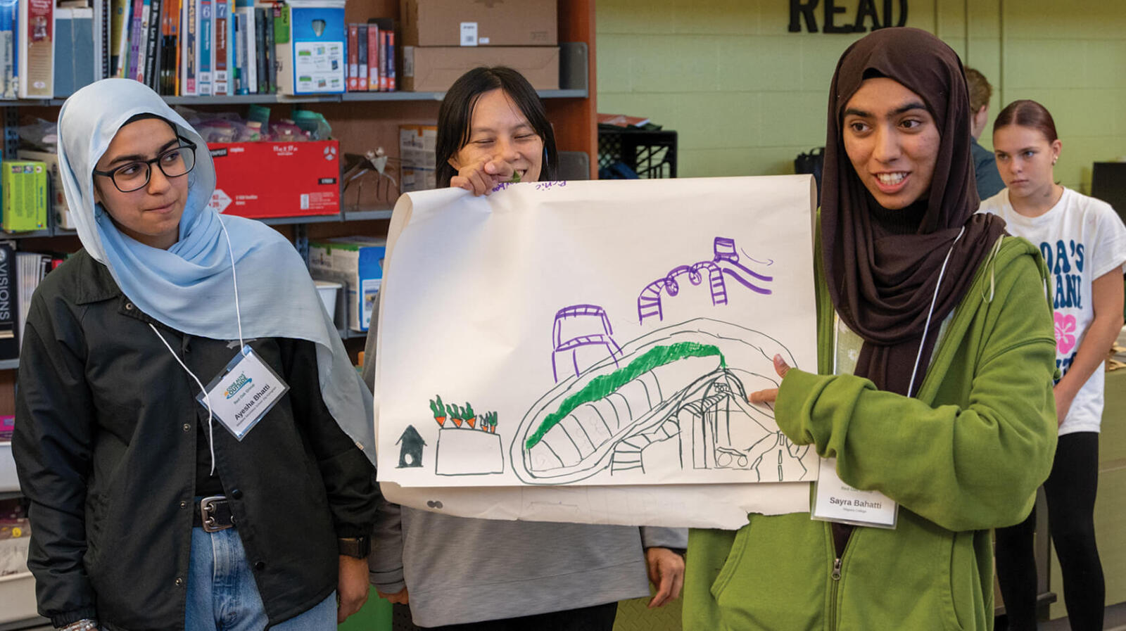 a young woman proudly displaying a drawing while other look on