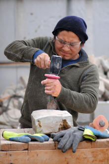 man chipping stone with chisel