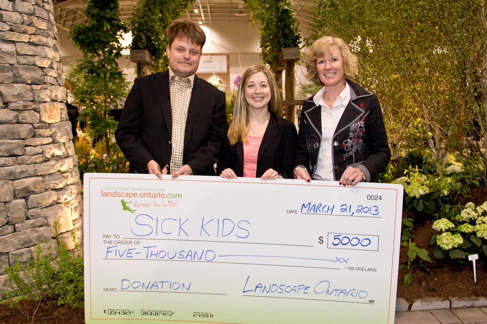 Arvils Lukss, Toronto Chapter president and Toronto Chapter past president Lindsay Drake Nightingale take time out during Canada Blooms to present Andrea Hoover, Child Life Department, Sick Kids (centre), with a $5,000 donation on behalf of the Chapter. Hoover plans to use the money to add an interactive component to the rooftop garden at the hospital by adding planting benches for children to monitor the growth rate of small plants and vegetables during their stay.