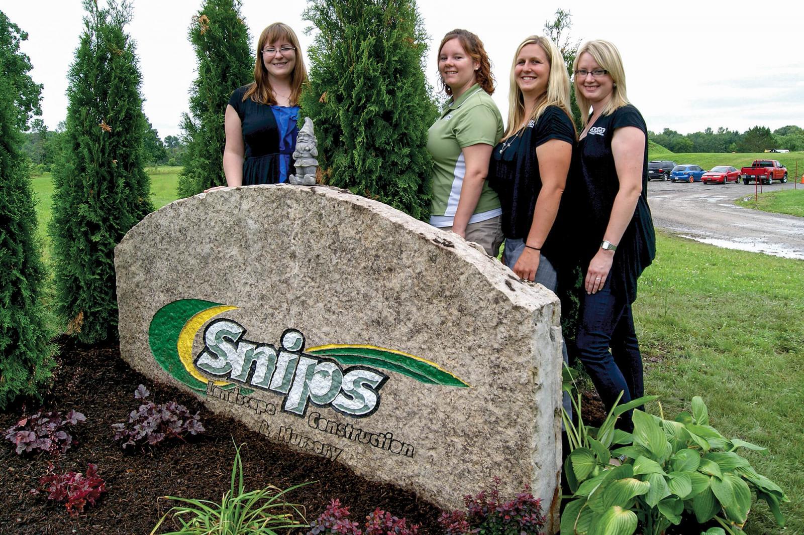 The ladies of Snips Landscape and Nursery, Alena Dawson, Tasha Beck, Kristi Montovani and Laura DeGraff, pose with what they call the tombstone, which greets visitors to Snips Landscape’s 10-acre site just outside Welland.